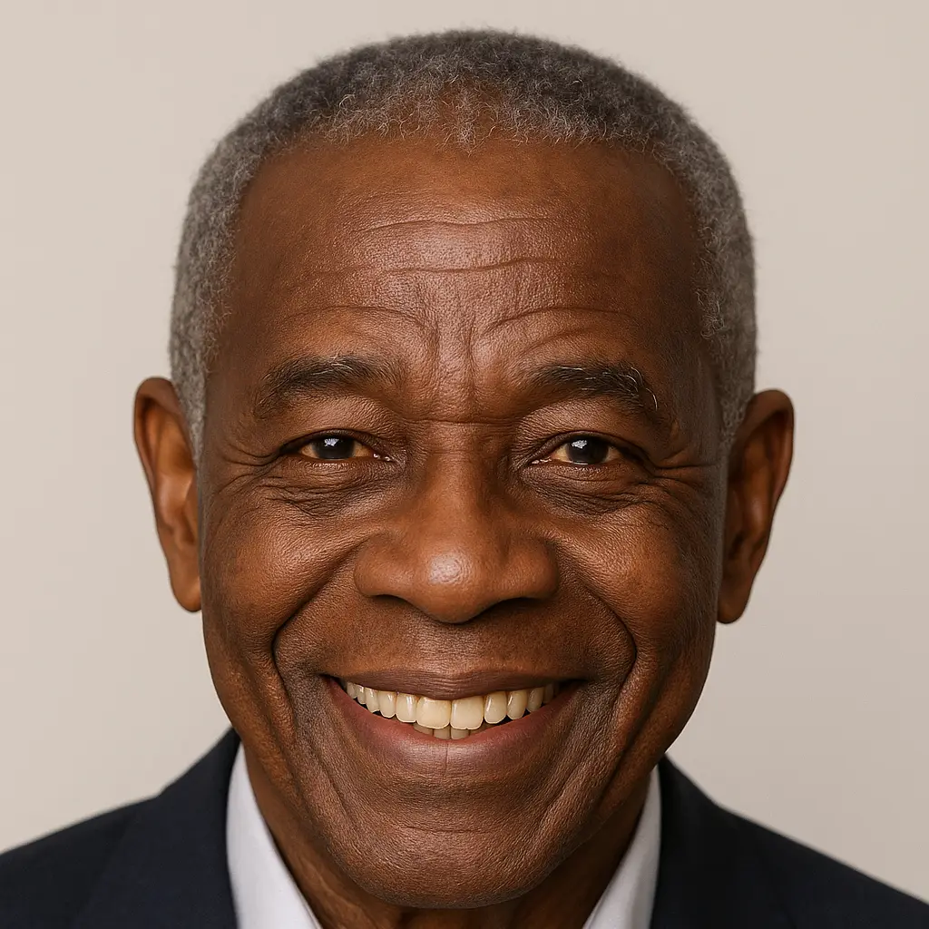 Homem mais velho sorridente de terno escuro, em retrato profissional com fundo neutro.